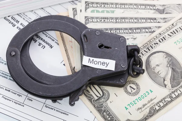 Handschellen und Geld mit Schild - Geld auf Steuerformularen Hintergrund — Stockfoto