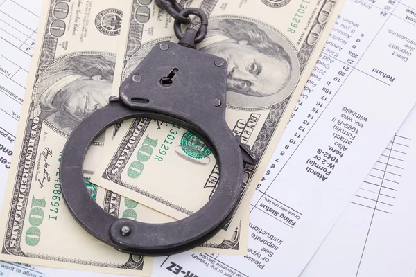 Viele Dollarscheine mit Handschellen, auf Steuerformular Hintergrund — Stockfoto