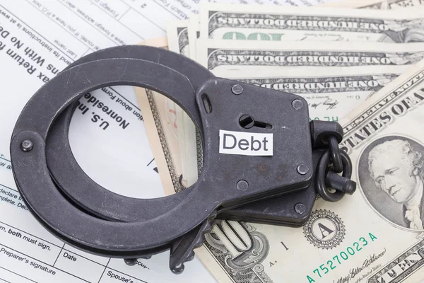 Handschellen und Geld mit Schild - Steuerschulden bilden Hintergrund — Stockfoto