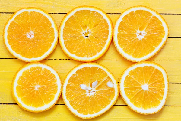 Sarı ahşap masa üzerinde taze portakal dilim — Stok fotoğraf