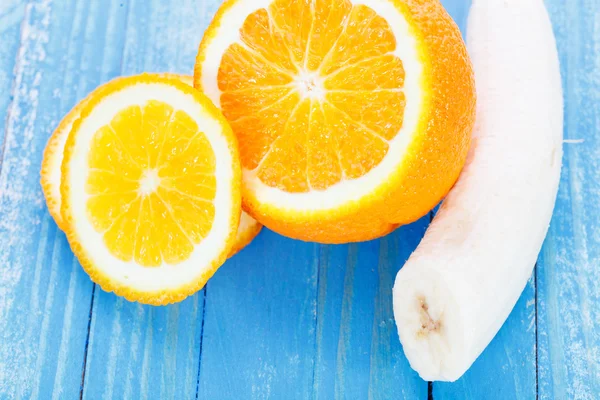 Orange frais avec banane sur table en bois bleu — Photo