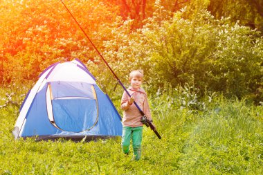 Sevimli küçük çocuk stand bir çadır onun elinde bir olta ile yakın.