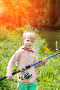 Onun elinde bir olta ile bir Nehri yakınında sevimli küçük çocuk standı.