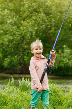 Onun elinde bir olta ile bir Nehri yakınında sevimli küçük çocuk standı.
