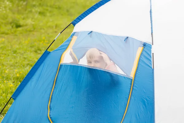 Un ragazzino carino in una tenda. Guarda attraverso la rete — Foto Stock