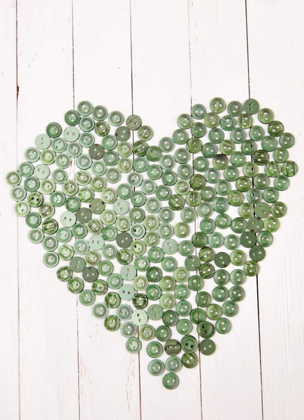 Coeur disposé à partir des boutons sur un fond blanc table en bois — Photo