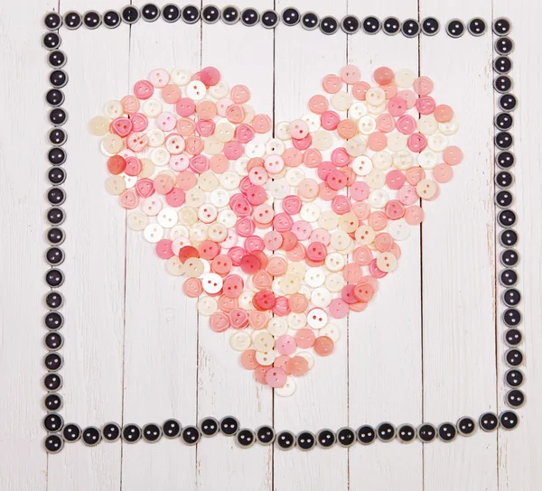 Heart laid out from the buttons  on a white background wooden table — Stock Photo, Image