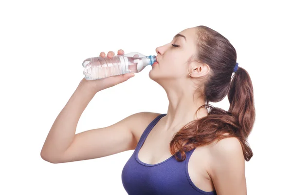 Beautiful athletic girl looks drinks water from a bottle — Stock Photo, Image