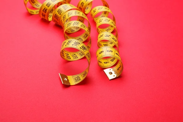 Yellow measuring tape on red background — Stock Photo, Image