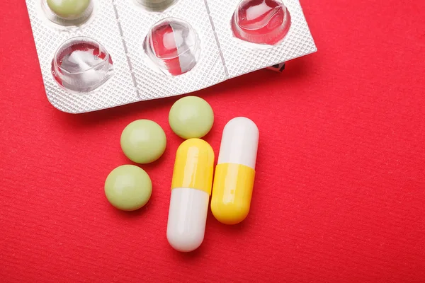 Pills and capsules on red background — Stock Photo, Image