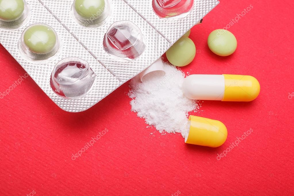 pills and capsules on red background