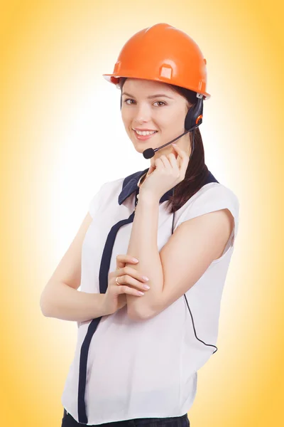 Jovem menina bonita em fones de ouvido com um microfone e um capacete de construção — Fotografia de Stock