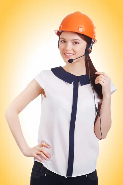 Jovem menina bonita em fones de ouvido com um microfone e um capacete de construção — Fotografia de Stock