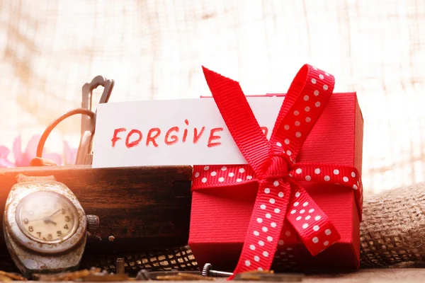 Red gift box tied red ribbon and text "Forgive" — Stock Photo, Image