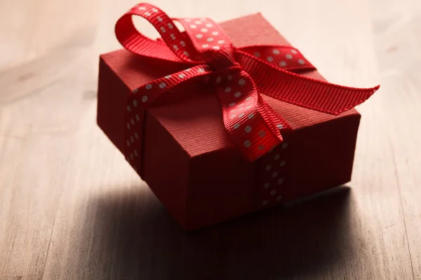 Caja de regalo roja atada cinta roja en mesa de madera — Foto de Stock