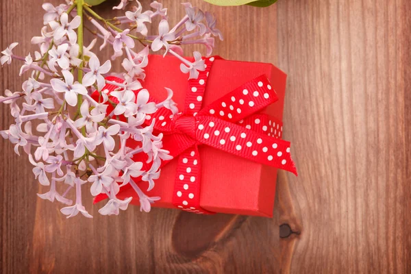 Caja de regalo roja atada cinta roja y flores sobre fondo de madera —  Fotos de Stock