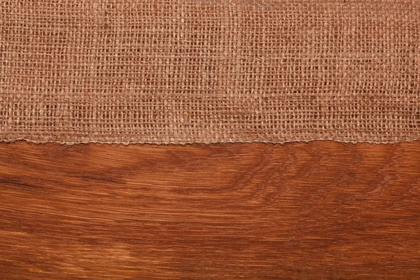 Burlap on wooden table — Stock Photo, Image