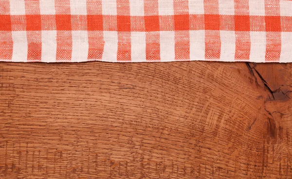 Mantel a cuadros rojo y blanco ondulado sobre mesa de madera — Foto de Stock