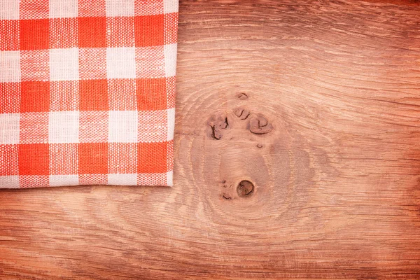 Tovaglia a quadretti rossa e bianca ondulata sul tavolo in legno — Foto Stock