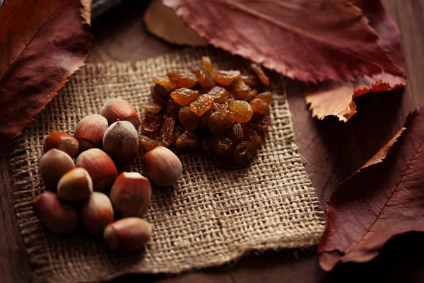Nocciole e uva passa con foglie autunnali sullo sfondo di un — Foto Stock