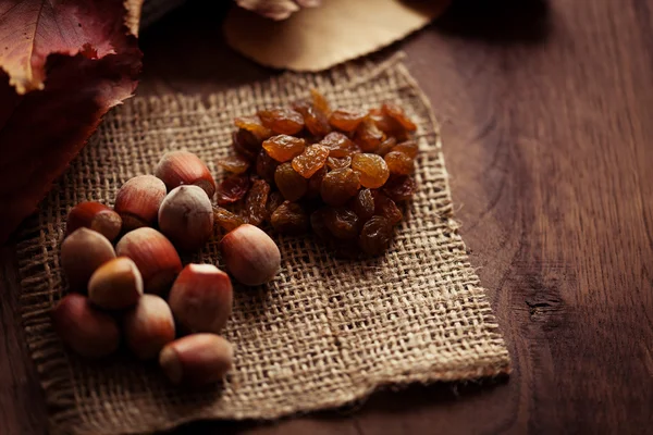 Nocciole e uva passa con foglie autunnali sullo sfondo di un — Foto Stock