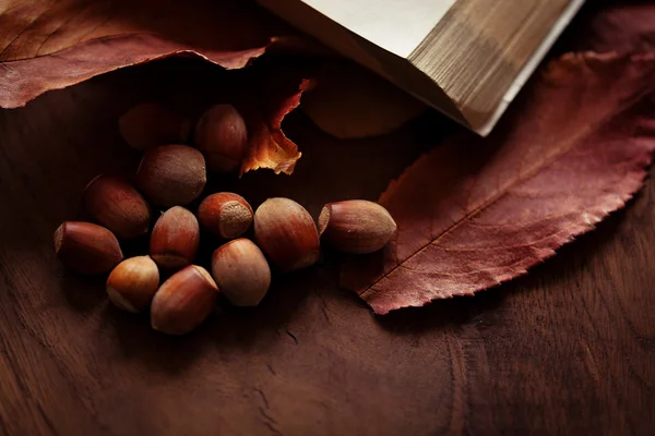 Nocciole con foglie autunnali sullo sfondo di una tavola di legno — Foto Stock