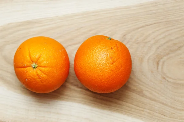 Dva pomeranče na dřevěný stůl — Stock fotografie