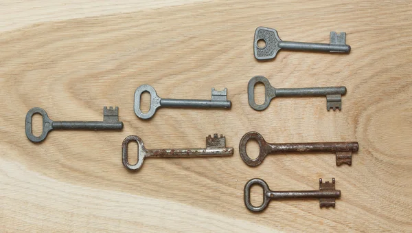Siete llaves dispuestas simétricamente sobre un fondo de madera — Foto de Stock