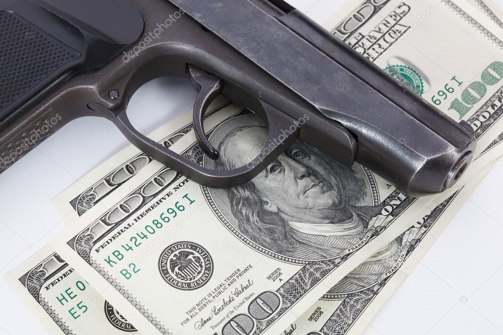 Black gun is lying on dollar bills