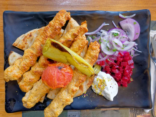 delicious spicy kebab plate with pita bread, peppers, tomatoes and tzatziki