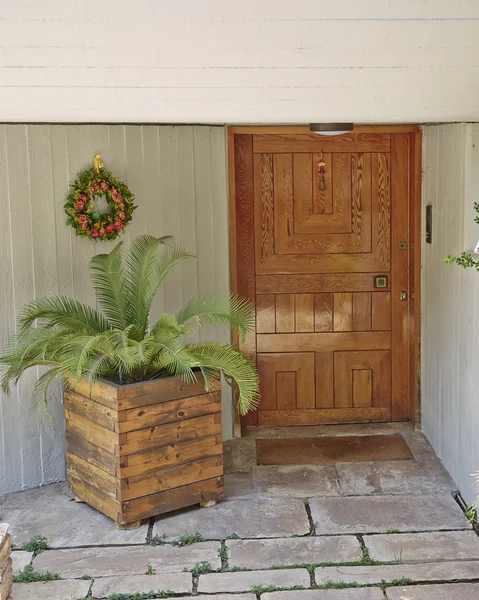 House entrance with solid wood door and flowerpot — Stock Photo, Image