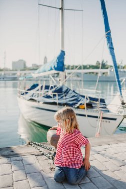 Sahilde kırmızı gömlekli küçük bir kız sahile bakıyor.