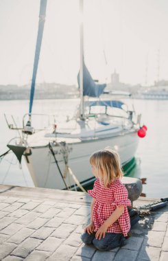 Sahilde kırmızı gömlekli küçük bir kız sahile bakıyor.