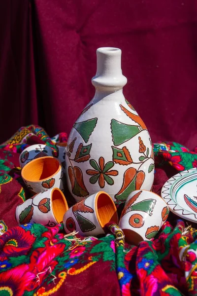 手工制作和手绘陶瓷陶瓷壶 长而薄的喷口 传统的波迪利亚抽象画 红色毛巾上的鸟图案 阳光直射 乌克兰传统民俗象征艺术 — 图库照片