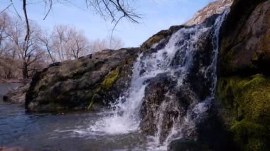 Küçük doğal şelale, granit taşlardan dökülen su yosunlarla kaplı sığ tatlı su deresine dökülüyor.