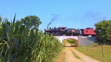 Strasburg, Pennsylvania, Temmuz 2020 - Güneşli bir yaz gününde yaklaşan Buhar Motorunun Dumanı ve Buharı Küçük bir Köprünün Üzerinden Geçiyor