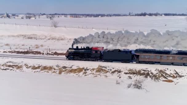 雪の嵐の後に乗用車を引っ張り煙と蒸気を吹いて接近するアンティーク蒸気機関車の空中ビュー — ストック動画
