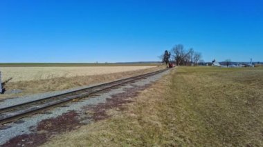 Güneşli bir kış gününde yalnız bir ray boyunca seyahat eden bir tren.