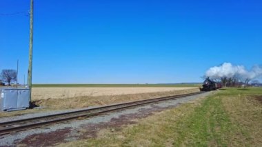 Yaklaşan Buharlı Yolcu Treni Güneşli bir günde duman ve buhar üflüyor