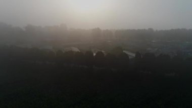 Sabahın erken saatlerinde çiftlik arazileri ve evleri üzerine yerleşen sisli bir hava manzarası