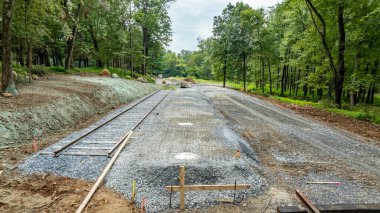 Ormanlık alanda yeni bir demiryolu hattı inşa ediliyor. İşçiler çakıl ve raylar döşüyorlar, gelecekteki gelişmeler için zemin hazırlıyorlar. Bölge yemyeşil ağaçlarla çevrili..