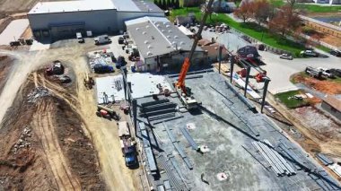 Gordonville, Pennsylvania, 4-9-2025 - Construction site in rural area shows active work with crane lifting materials. Workers are busy on the framework of new building, surrounded by fields and homes.