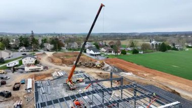 Gordonville, Pennsylvania, 9 Nisan 2025 işçiler inşaat alanında çelik kirişleri taşımak için vinç kullanıyorlar. Ayarlar arka planda çiftlik arazileri ve evleri gösteriyor.