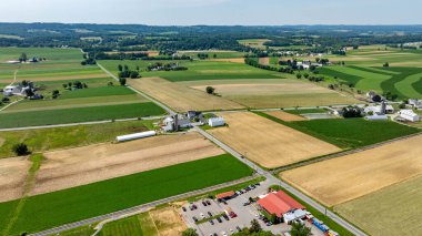 Arazi boyunca geniş yeşil ve kahverengi alanlar, çiftlik binaları ve yollarla noktalanmış. Kenarda küçük bir park alanı görünüyor, bu da alan erişimini gösteriyor..