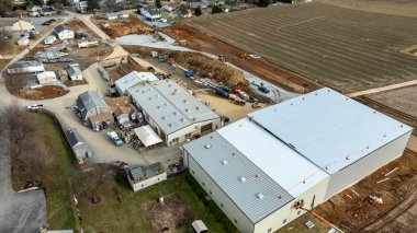 Kırsal alanda hareketli bir inşaat alanı. Sergide çok sayıda bina, ağır makineler ve açık gökyüzü altında gerçekleşen etkin gelişmeler yer alıyor..