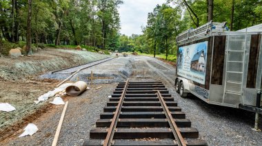 Çakıl taşlarının üzerine yeni döşenmiş rayların yer aldığı ormanlık bir bölgeden geçen bir demiryolu hattında inşaat devam ediyor..