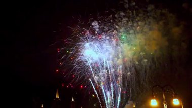 Parlak havai fişekler çeşitli renklerde patlayıp şehir merkezinin üstündeki gece gökyüzünü aydınlatıyor. Seyirciler huşu içinde izlemektedirler. Canlı gösteri geceye neşe ve sevinç getirmektedir..