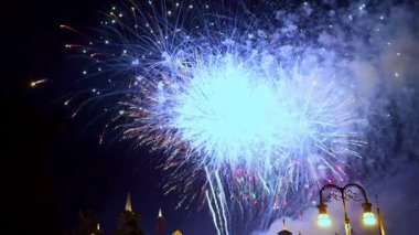 Canlı bir şehir parkının üzerindeki gece gökyüzünü aydınlatan çeşitli renklerde parlak havai fişekler bir akşam festivali sırasında patladı. Aileler ve arkadaşlar bu muhteşem gösterinin tadını çıkarmak için bir araya geldiler..