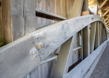 Ahşap kirişler inşaat alanında belli bir düzende dizilir. Yapı, inşa edilen bir binanın iskeletini gösteriyor. Güneş ışığı ormandaki boşluklardan gelir..