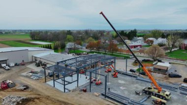 Gordonville, Pennsylvania, 9 Nisan 2025 inşaat işçileri açık bir alanda yeni bir yapı üzerinde çalışmak için büyük makineler kullanıyorlar. Metal çerçeveleri kaldırıp yerlerine yerleştiriyorlar. Çevreleme